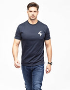 A man wearing a dark navy blue short-sleeve t-shirt with a white geometric logo on the left chest, paired with blue jeans, photographed against a plain white background.