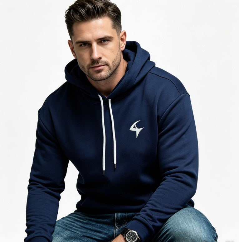 A man wearing a navy blue pullover hoodie with white drawstrings and a white stylized logo on the left chest, paired with blue jeans, set against a plain white background.